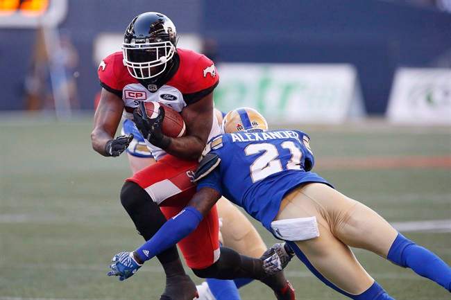 Calgary Stampeders' Jerome Messam (33) dodges a tackle by Winnipeg Blue Bombers' Brandon Alexander (21) during first half CFL action, in Winnipeg on Friday, July 7, 2017.