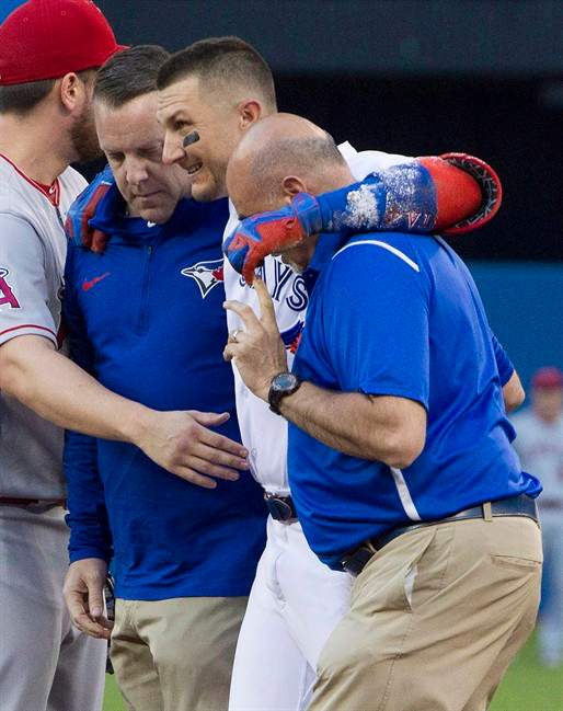 Toronto Blue Jays' Troy Tulowitzki, centre, is helped off the field by trainers Mike Frostad, left, and George Poulis after he injured himself awkwardly running across the first base during a game on Friday, July 28, 2017.