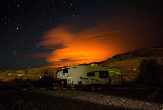 FILE PHOTO: A trailer parked at a campground in Savona, B.C., is seen as the Elephant Hill wildfire burns in the distance.