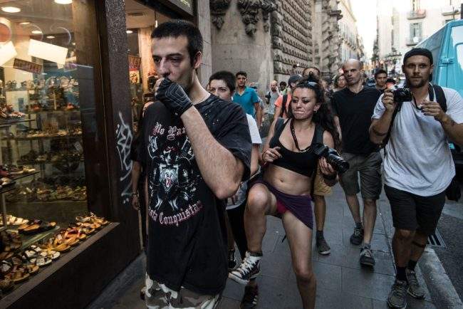 An anti-fascist activist kicks a man who is claimed to be a right-wing sympathiser as he walks from the scene of the terrorist attack on Las Ramblas in Barcelona, Spain, Aug. 18, 2017.