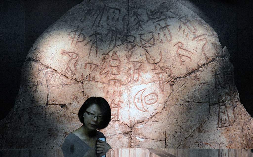 A woman walks past an enlarged picture of Oracle bones script from 1,200 BC during an exhibition about "King Wu Ding and Lady Hao: Art and Culture of the late Shang Dynasty" on display at the National Palace Museum in Taipei.