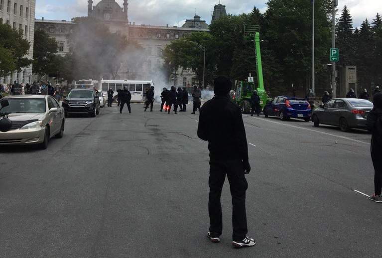 Counter-protesters throw smoke bombs and fire works towards police in Quebec City. Sunday, Aug. 20, 2017.