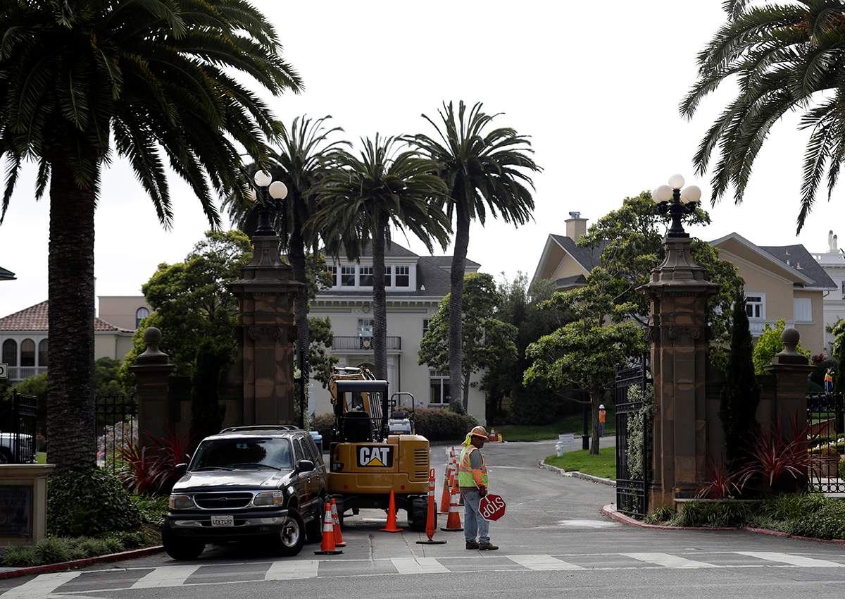 A construction workers stands in front of a gate leading into the Presidio Terrace neighborhood Monday, Aug. 7, 2017, in San Francisco.