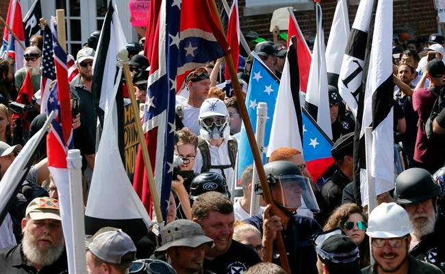 White nationalist demonstrators walk into the entrance of Lee Park surrounded by counter demonstrators in Charlottesville, Va., Saturday, Aug. 12, 2017. Gov. Terry McAuliffe declared a state of emergency and police dressed in riot gear ordered people to disperse after chaotic, violent clashes between white nationalists and counter-protestors.