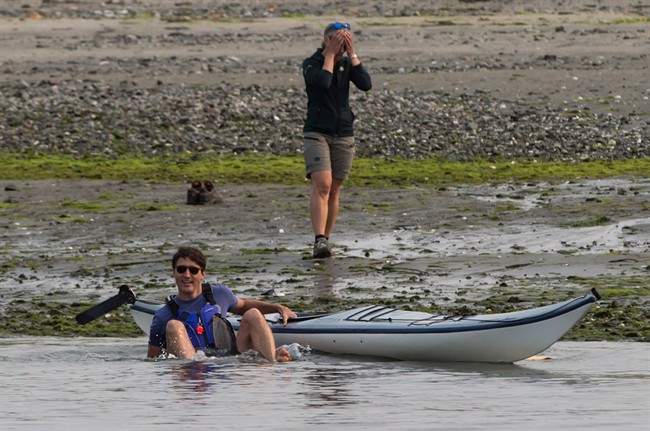 A Parks Canada staff member, back, reacts after Prime Minister Justin Trudeau fell into the water while trying to get into a kayak at Sidney Spit in the Gulf Islands National Park Reserve, east of Sidney, B.C., on Saturday August 5, 2017.