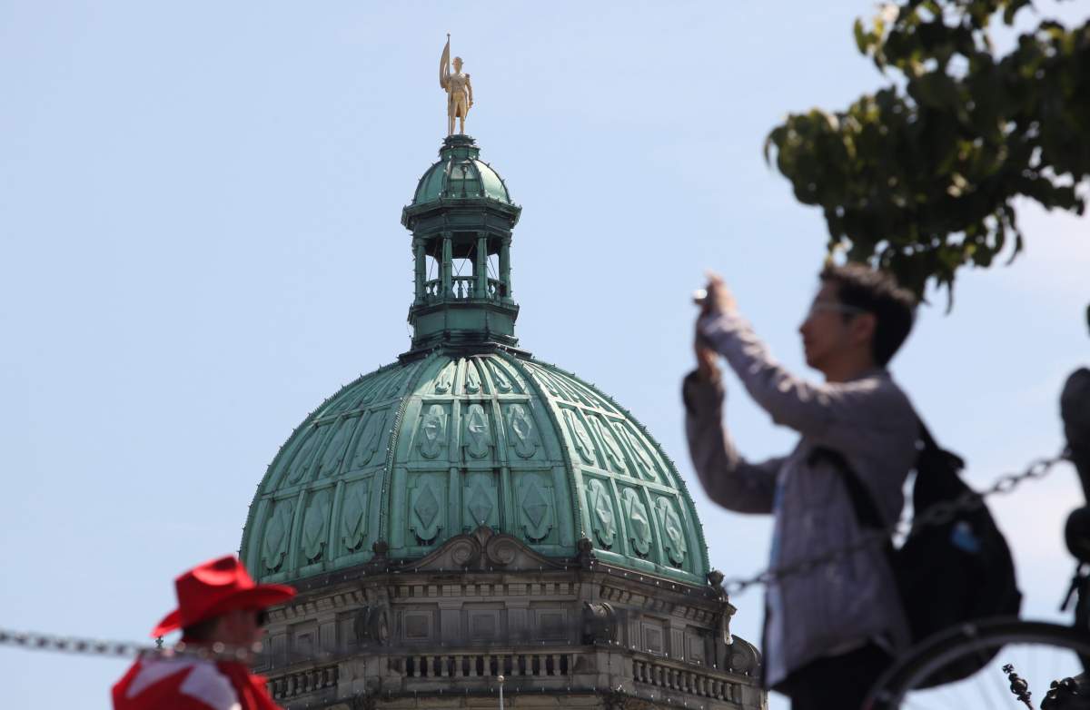 The B.C. Legislative building sets the backdrop as tourist takes pictures on Canada Day, in Victoria, B.C., July 1, 2011.