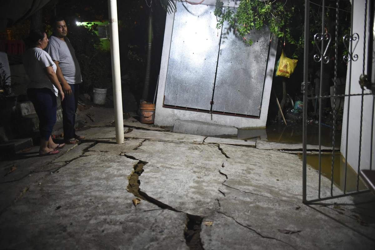 A couple looks at the damaged floor of their yard in Coatzacoalcos, in the Veracruz state of Mexico, after a 8.2 magnitude earthquake violently shook Mexico, early 08 September 2017.