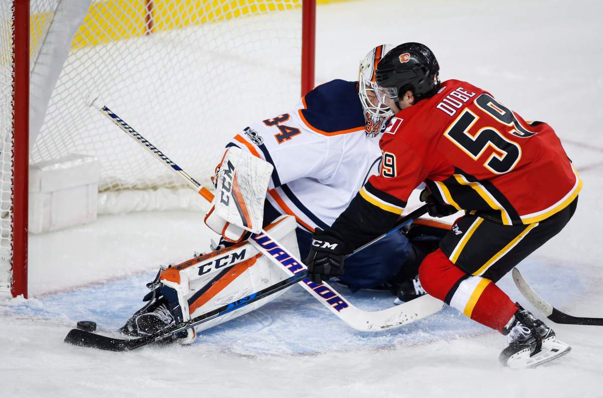 Edmonton Oilers goalie Nick Ellis, left, stops Calgary Flames forward Dillon Dube from scoring during third period NHL preseason split-squad hockey action in Calgary, Monday, Sept. 18, 2017.