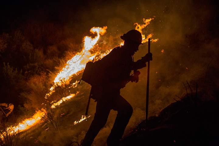 A firefighter climbs a burning hillside after having fallen into a pit fighting while the La Tuna Fire on September 2, 2017 near Burbank, California.