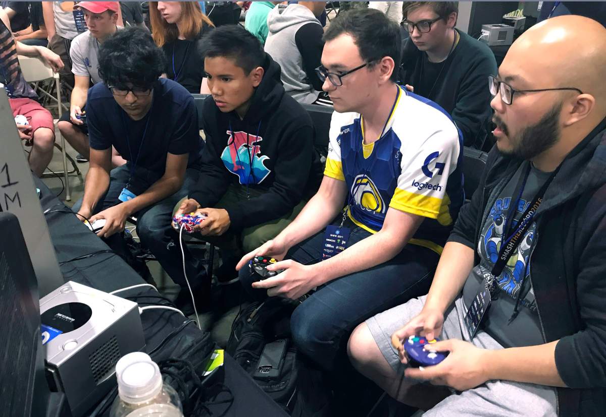 In this Aug. 25, 2017, photo, Connor Nguyen, at right, and Griffin Williams, second from right, compete in a “Super Smash Bros. Melee” tournament at the Shine eSports festival at the Seaport World Trade Center in Boston. Griffin, 21, is captain of an esports team at the University of California, Irvine, and Nguyen, 23, is a graduate of the school. The University of California, Irvine, is among a growing number of U.S. schools starting to offer at least partial scholarships to students who compete in esports, competitive video-game playing.