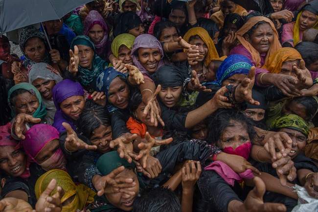 Rohingya Muslim women, who crossed over from Myanmar into Bangladesh, stretch their arms out to collect sanitary products distributed by aid agencies near Balukhali refugee camp, Bangladesh, Sunday, Sept. 17, 2017.