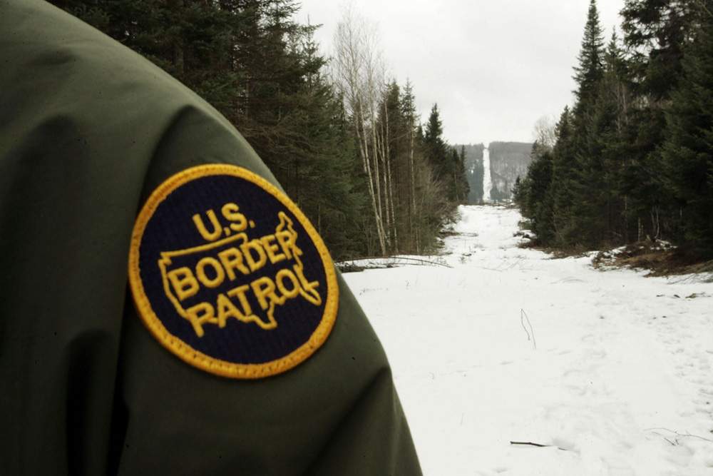 A U.S. Border Patrol agent stands along the boundary marker cut into the forest near Beecher Falls, Vermont in this file image. 
