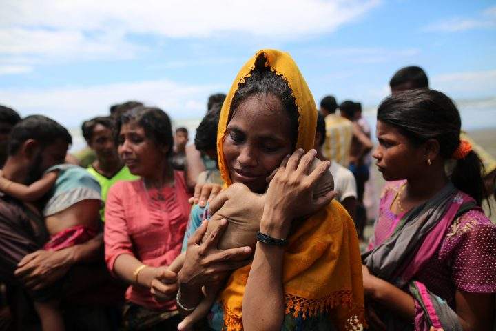 A Rohingya Muslim woman holds an infant child who died when the boat they were traveling in capsized.