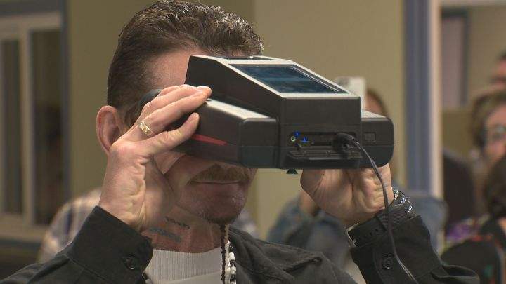 Four Directions Financial client Bryan Kenny shows off the biometric technology at the branch.