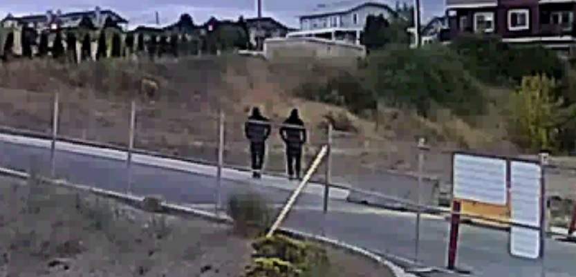 In this image image from a surveillance camera near Hudson’s Bay Trail, police said that two suspects are seen walking across a field to the victim’s home.