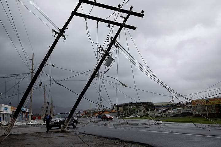 A police officer walks next to damaged electrical boxes in Guayama, Puerto Rico after the island was hit by Hurricane Maria, September 20, 2017.