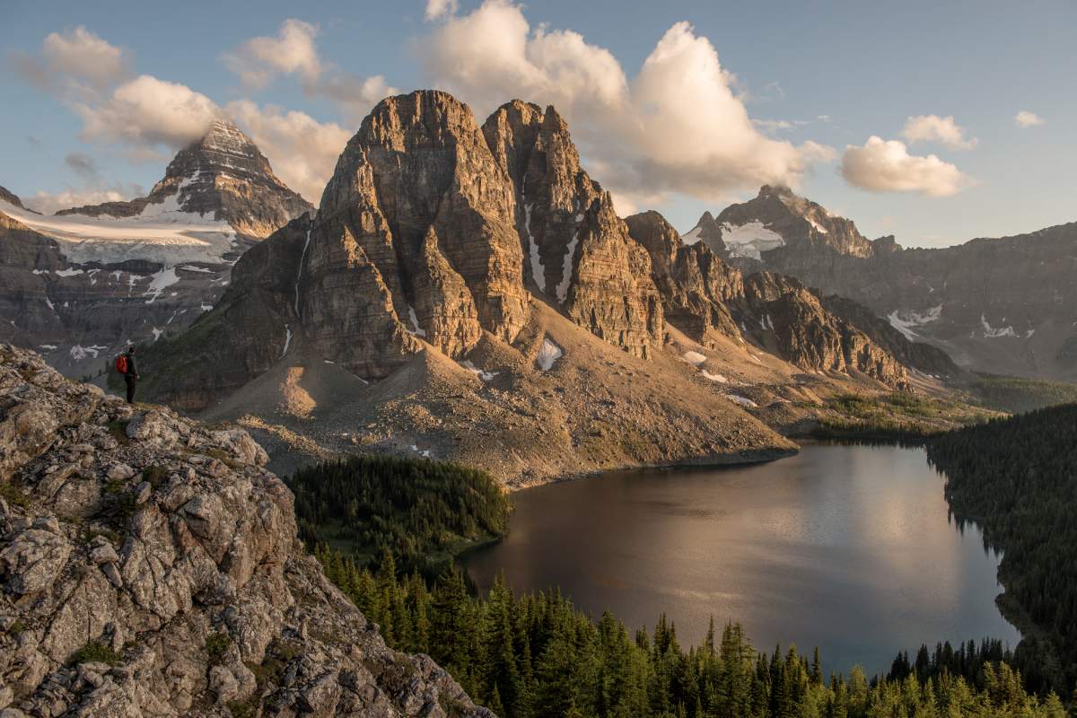 A hiker on the trail to Nublet and Nub Peak, with views of Cerulean Lake, Sunburst Peak and Mt Assiniboine, Assiniboine Provincial Park, B.C.