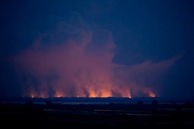 In this Sept. 3, 2017, file photo, smoke and flames in Myanmar are visible from the Bangladeshi side of the border near Cox’s Bazar’s Teknaf area.