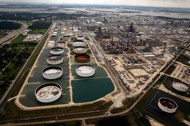 FILE - In this Wednesday, Aug. 30, 2017 file photo, large storage tanks situated in retention ponds are surrounded by rainwater left behind by Tropical Storm Harvey at ExxonMobil's refinery in Baytown, Texas.