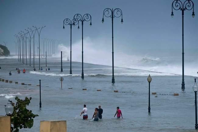 Residents walk on Havana's sea wall as the ocean crashes into it, after the passing of Hurricane Irma in Cuba, Sept. 10, 2017.