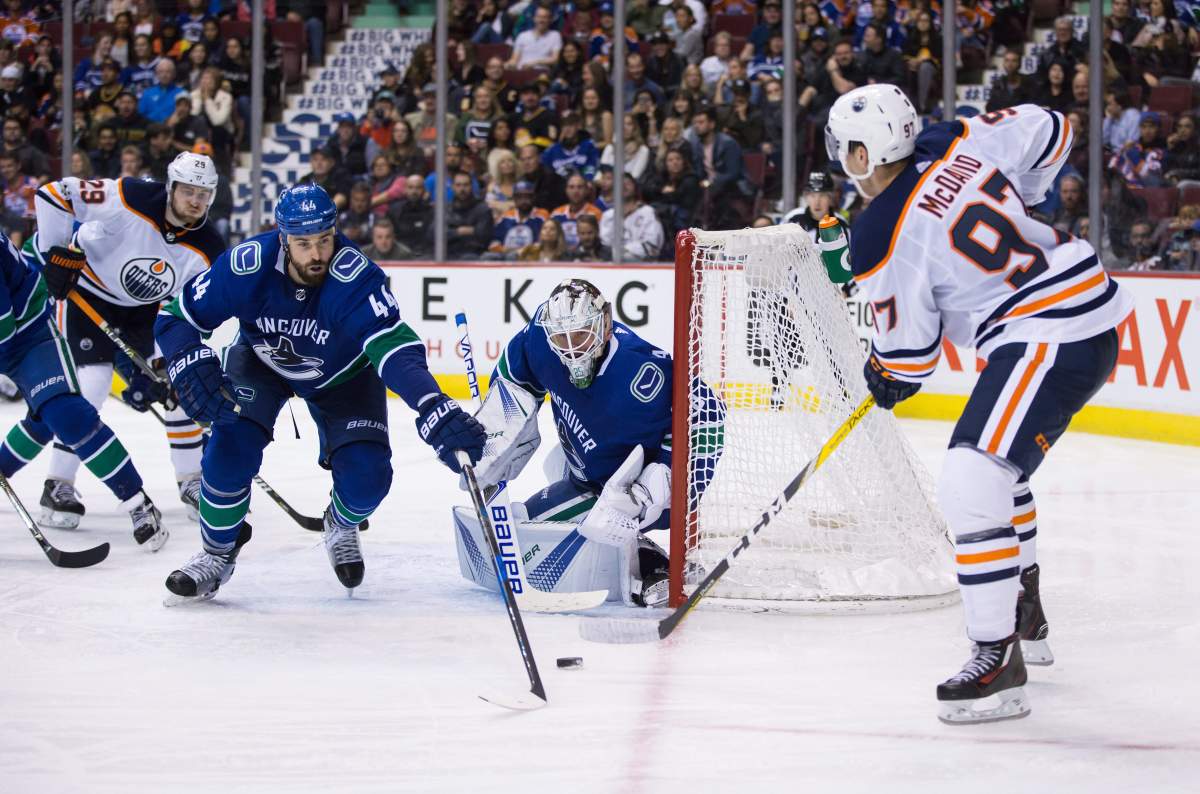 Edmonton Oilers' Connor McDavid, right, is stopped by Vancouver Canucks' goalie Jacob Markstrom, of Sweden, as Erik Gudbranson (44) defends during the third period of a preseason NHL hockey game in Vancouver, B.C., on Saturday September 30, 2017. THE CANADIAN PRESS/Darryl Dyck.
