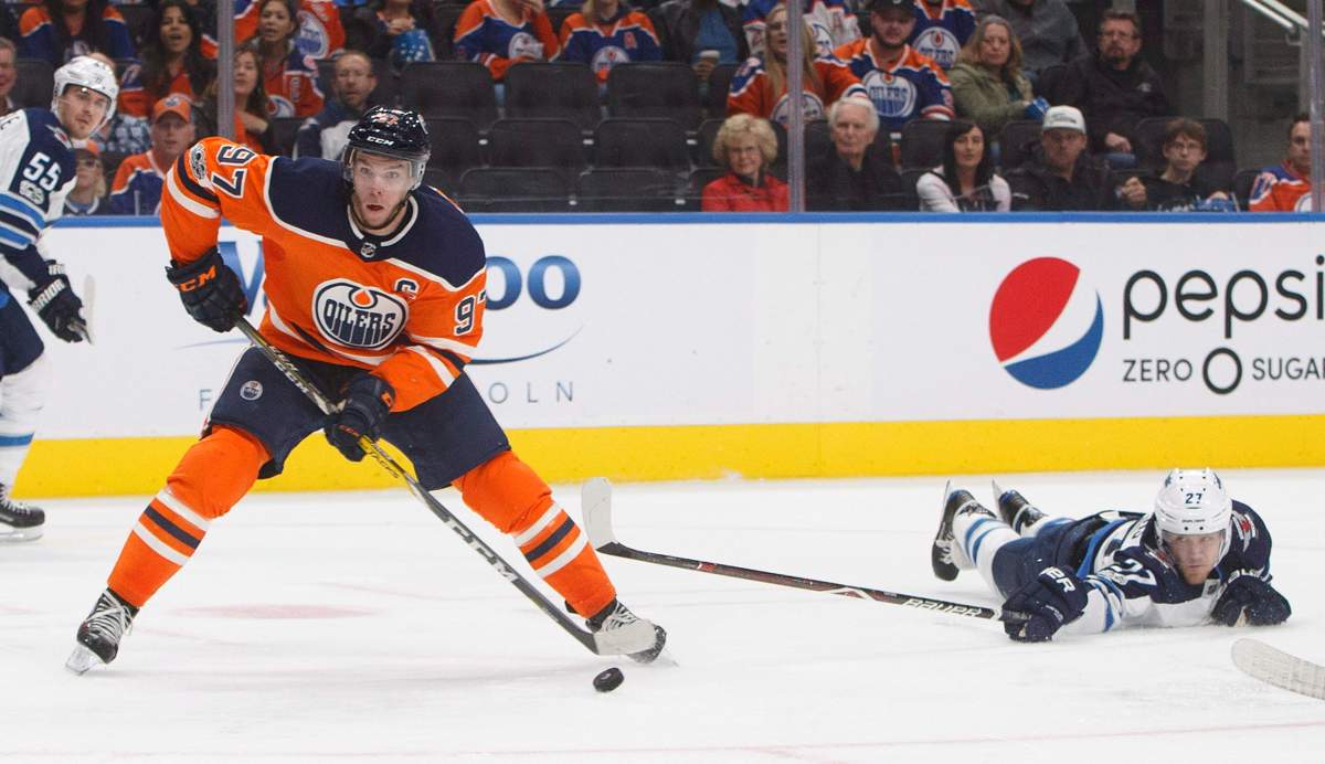 Winnipeg Jets' Nikolaj Ehlers (27) reaches for Edmonton Oilers' Connor McDavid (7) during second-period NHL action in Edmonton on Oct. 9, 2017.