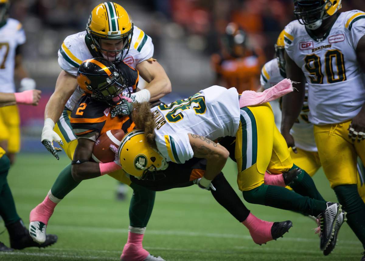 Edmonton Eskimos’ Adam Konar, back left, and Aaron Grymes, right, tackle B.C. Lions’ Chris Rainey (2) during the second half of a CFL football game in Vancouver, B.C., on Saturday October 21, 2017. THE CANADIAN PRESS/Darryl Dyck