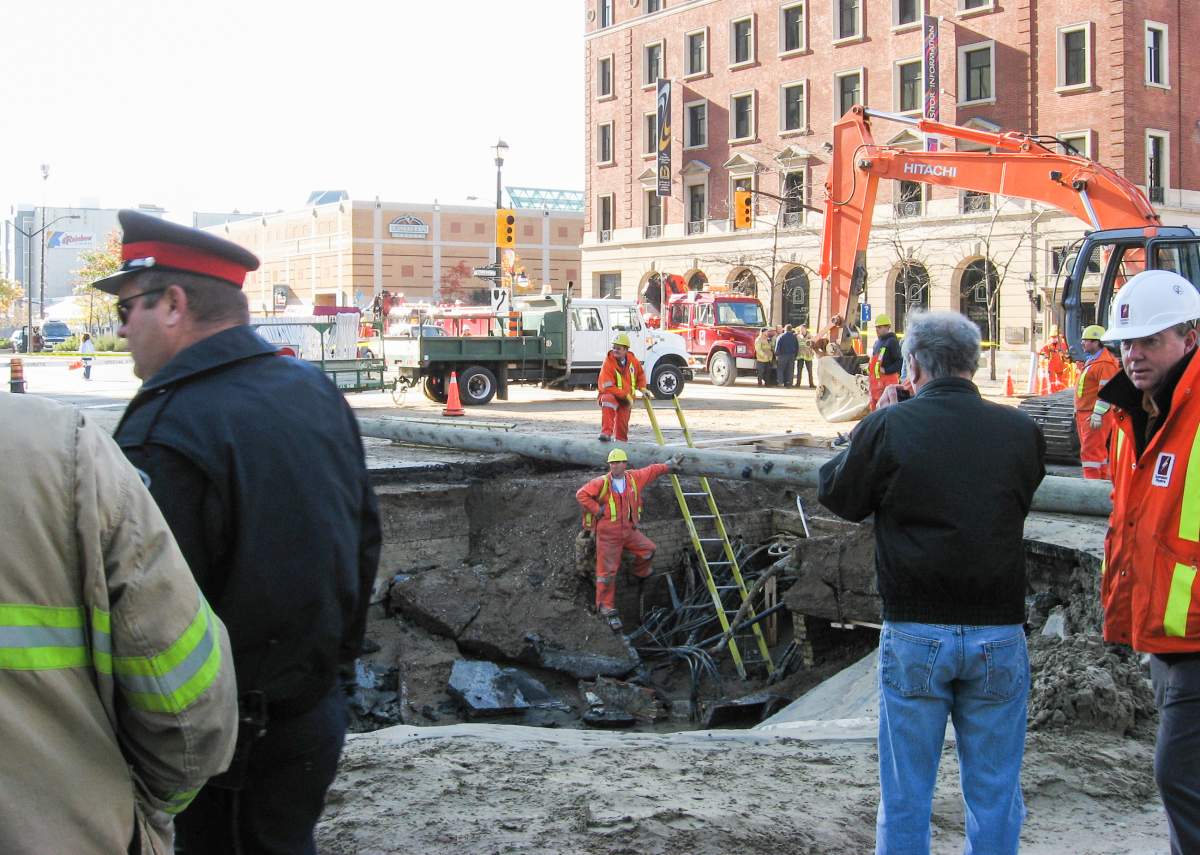 Workers stand around, and in, a giant sinkhole at the intersection of Wellington and Dundas streets, Oct. 31, 2007