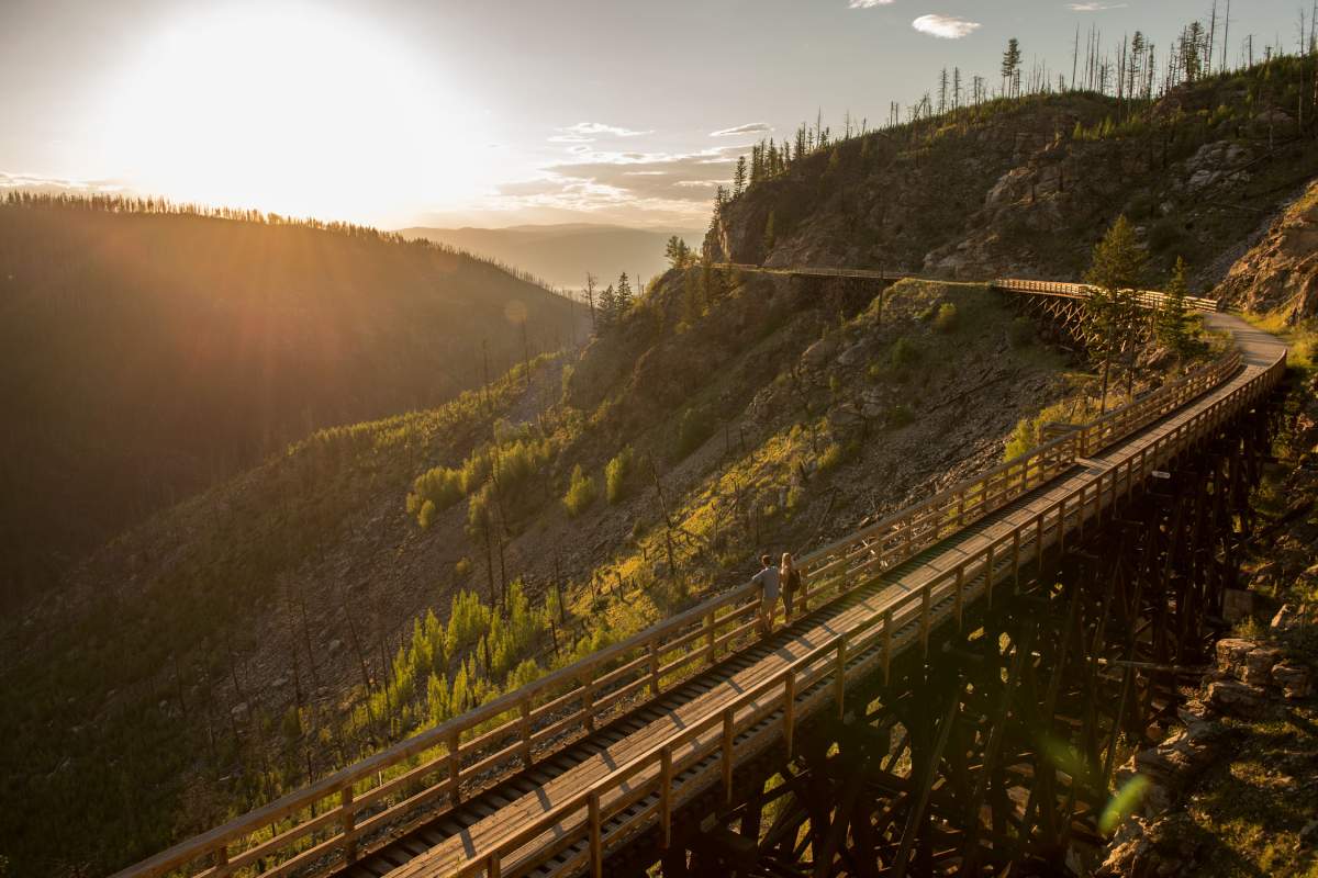 A couple enjoys the sunset on one of the trestle bridges overlooking Myra Canyon on the Kettle Valley Railway,