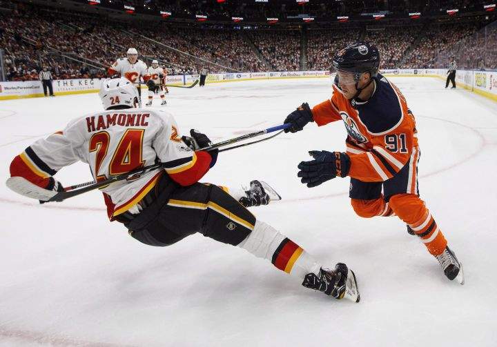 Calgary Flames' Travis Hamonic (24) is knocked down by Edmonton Oilers' Drake Caggiula (91) during second period NHL action in Edmonton, Alta., on Wednesday October 4, 2017. 