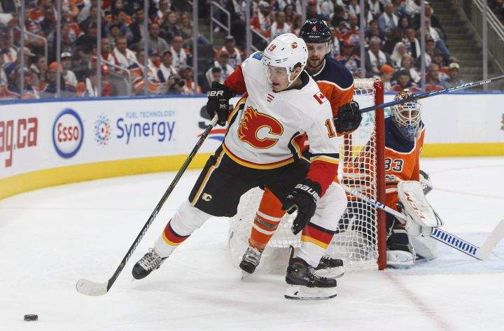 Calgary Flames’ Matthew Tkachuk (19) and Edmonton Oilers’ Kris Russell (4) battle for the puck during first period NHL action in Edmonton, Alta., on Wednesday October 4, 2017.