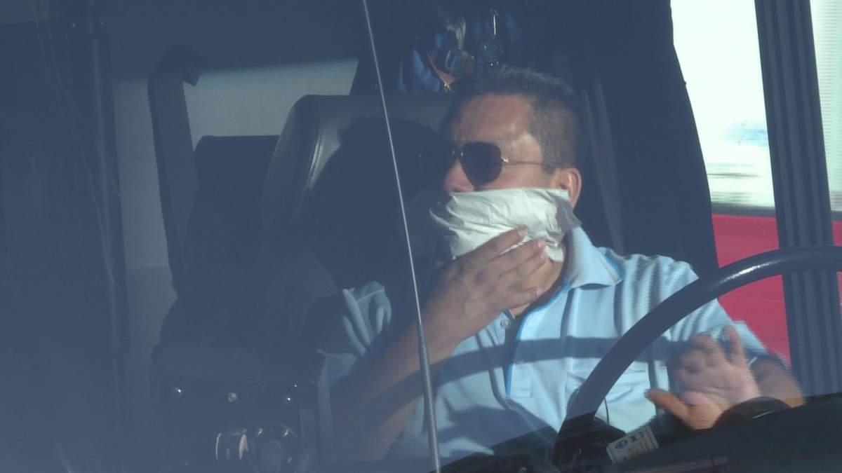 A Montreal bus driver covers his face and honks his horn to support protesters of the province's controversial Bill 62, which would force people to have their faces uncovered to receive services, Friday, Oct. 20, 2017. The driver could face sanctions for his actions. 