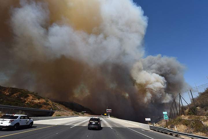A police car blocks the 241 freeway as smoke from the Canyon 2 Fire covers the road near Orange, California, October 9, 2017.