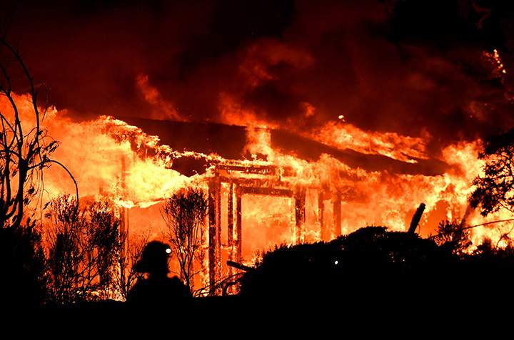 Firefighters assess the scene as a house burns in the Napa wine region of California on October 9, 2017.