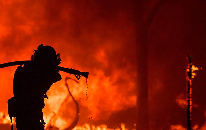 A firefighter pulls a hose in front of a burning house in the Napa wine region of California on October 9, 2017.