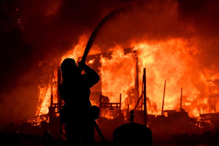 A firefighters douses flames as a home burns in the Napa wine region of California on October 9, 2017.