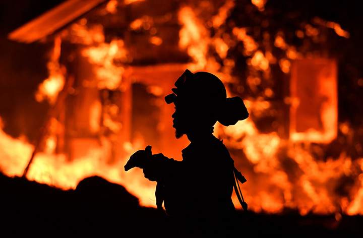 A firefighter monitors flames as a house burns in the Napa wine region in California on October 9, 2017.