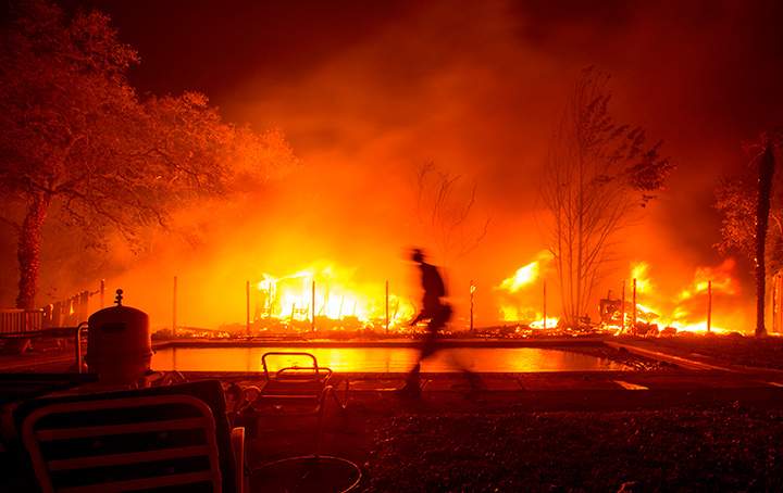 A firefighter walks near a pool as a neighbouring home burns in the Napa wine region in California on October 9, 2017.
