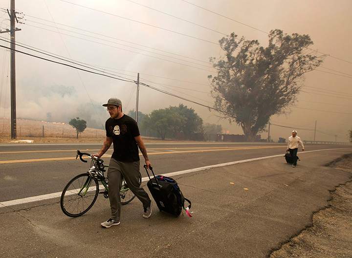 Residents evacuate as flames from a massive wildfire approach their homes Monday, Oct. 9, 2017, in Napa, California.