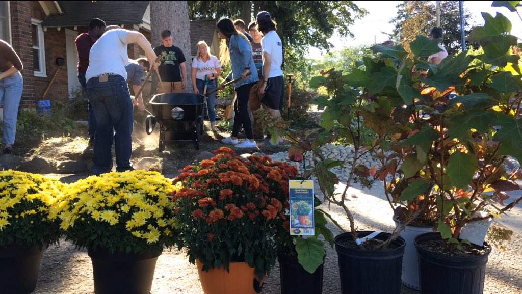 Volunteers help create a circular rock pattern, before planting new flowers on Bess Shahulek's front lawn.