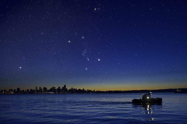 The constellation Orion setting after dusk over the Vancouver skyline.