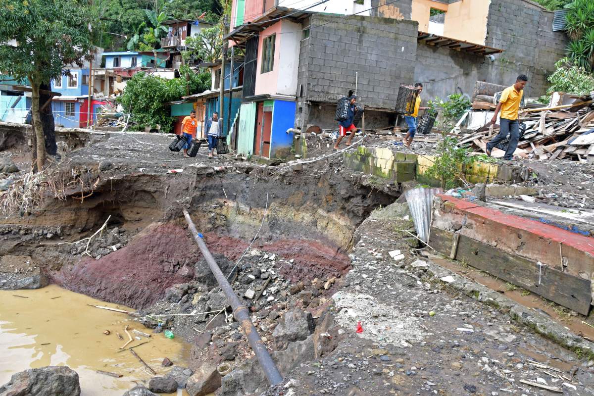 People walk next to an area destroyed by a landslide caused by heavy rains during Tropical Storm Nate in the Los Anonos neighbourhood of San José, Costa Rica, on Oct. 6.
