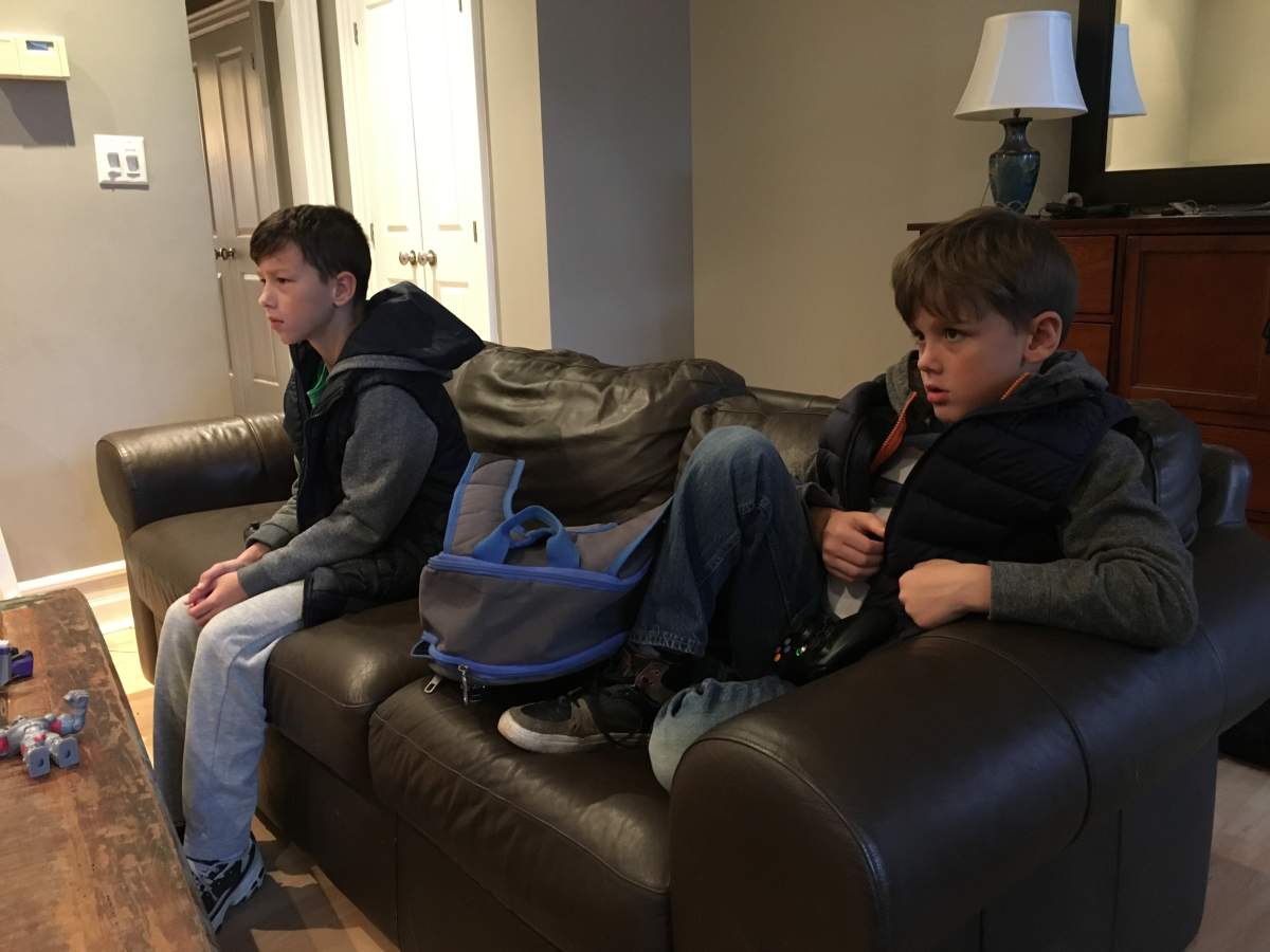 Kaleb (foreground) and Joshua Haughton spend another morning ready for school but watching cartoons as they wait for their school bus to arrive.