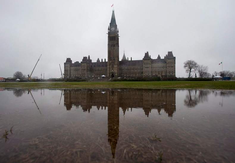 Parliament Hill is reflected in a puddle on the front lawn during a rainstorm in Ottawa in April 2017.