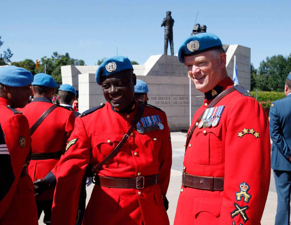 RCMP Cpl. Kofi Gordon, left, who served as a peacekeeper in the Democratic Republic of the Congo and Haiti, and Sergeant Ron Rose, who served as a peacekeeper in Haiti, pose for photos at the National Peacekeeping Monument.