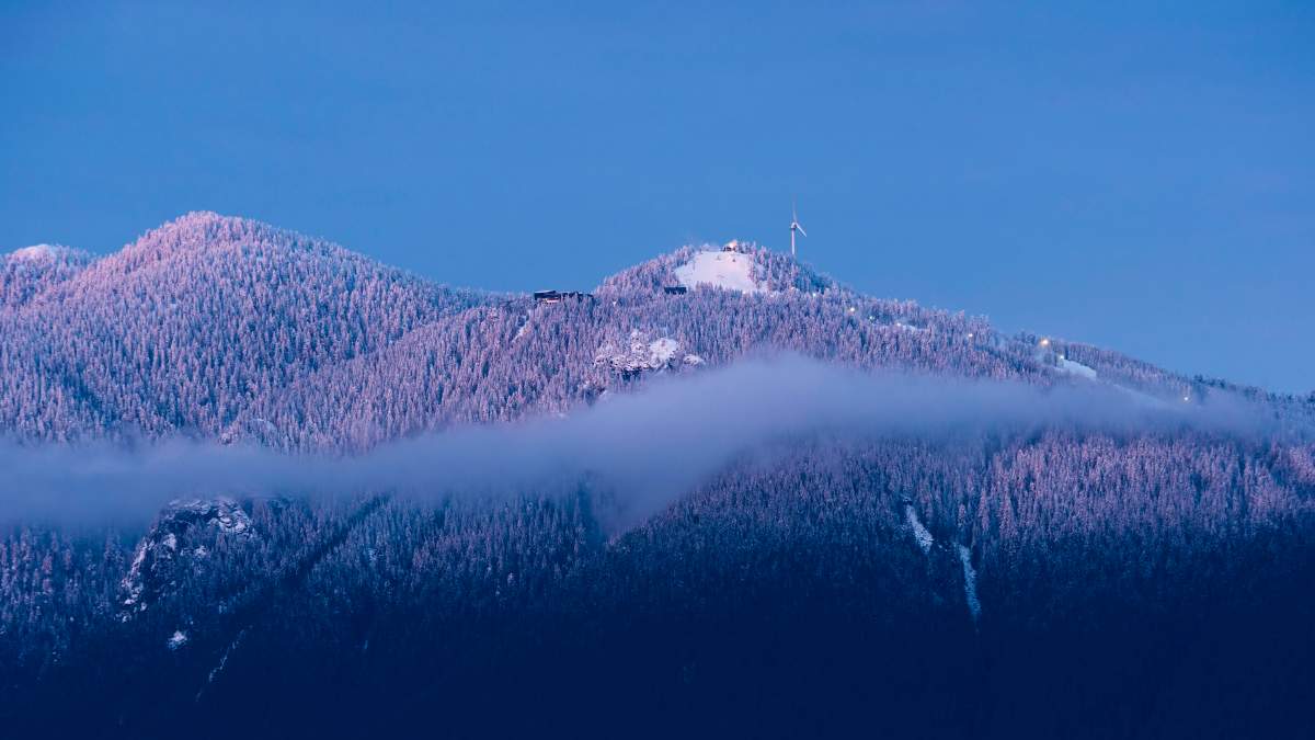 Sunset colours light up fresh snow on the peaks of Vancouver’s North Shore Mountains, including the Grouse Mountain ski runs, North Vancouver, B.C., February 2, 2016.