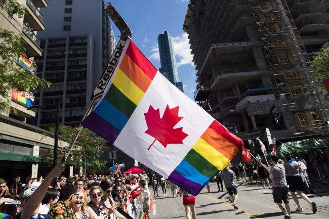 A man holds a flag on a hockey stick during the Pride parade in Toronto on June 25, 2017.