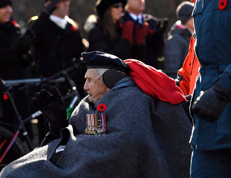 A veteran waves as he participates in the march during the National Remembrance Day Ceremony in Ottawa on Saturday, Nov. 11, 2017. 