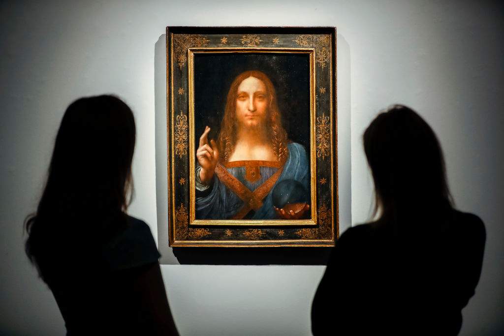 Christie's employees pose in front of a painting entitled Salvator Mundi by Italian polymath Leonardo da Vinci at a photocall at Christie's auction house in central London on October 22, 2017 ahead of its sale at Christie's New York on November 15, 2017. 