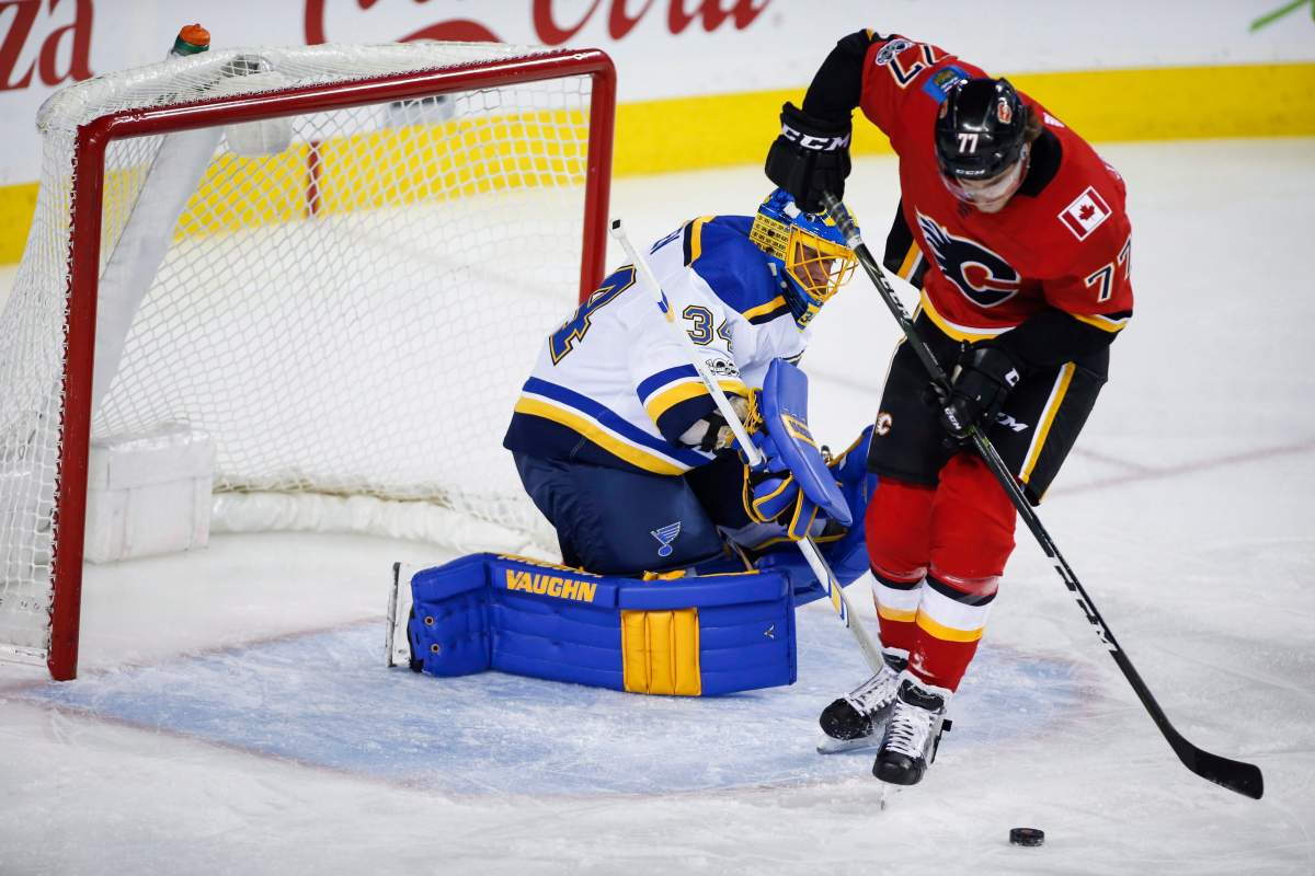 St. Louis Blues goalie Jake Allen, left, looks on as Calgary Flames' Mark Jankowski chases a loose puck during first period NHL hockey action in Calgary, Monday, Nov. 13, 2017. THE CANADIAN PRESS/Jeff McIntosh.